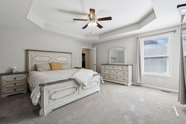carpeted bedroom with a raised ceiling, visible vents, a ceiling fan, and baseboards