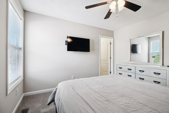 carpeted bedroom with baseboards, a ceiling fan, visible vents, and a textured ceiling