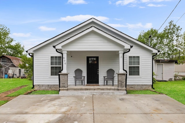 bungalow-style house featuring covered porch and a front yard