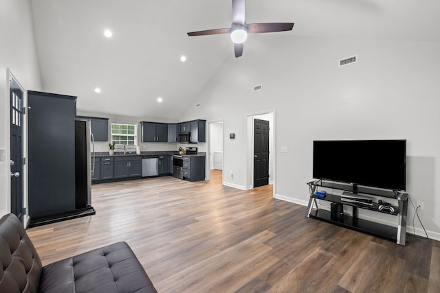 living area with light wood-style flooring, visible vents, a ceiling fan, and high vaulted ceiling