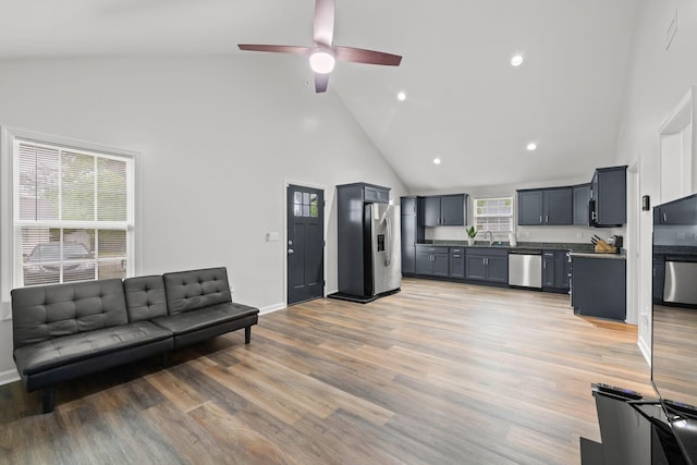 living area with light wood finished floors, recessed lighting, high vaulted ceiling, a ceiling fan, and baseboards