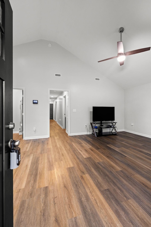 unfurnished living room featuring a ceiling fan, visible vents, wood finished floors, and high vaulted ceiling