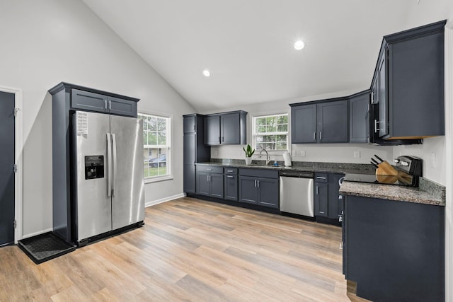kitchen with a sink, appliances with stainless steel finishes, light wood-style floors, recessed lighting, and high vaulted ceiling