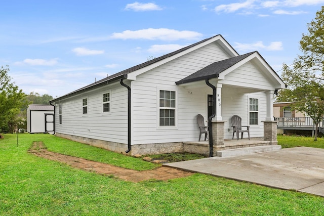 bungalow-style house with covered porch, an outdoor structure, a shed, and a front yard