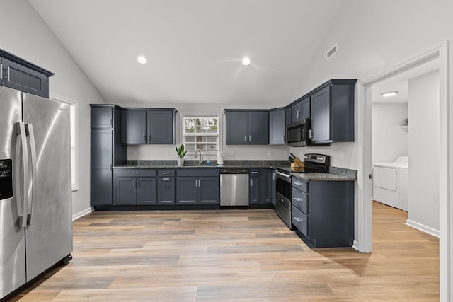 kitchen featuring lofted ceiling, a sink, visible vents, stainless steel appliances, and separate washer and dryer