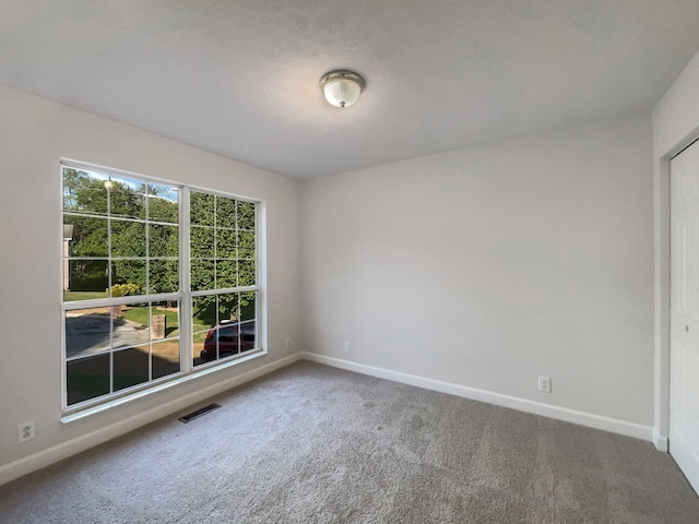 spare room with baseboards, carpet flooring, and visible vents