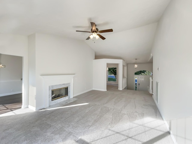 unfurnished living room with vaulted ceiling, baseboards, ceiling fan with notable chandelier, carpet floors, and a high end fireplace