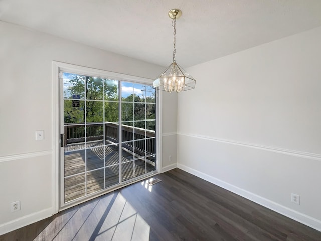 unfurnished dining area featuring an inviting chandelier, dark wood-style flooring, and baseboards