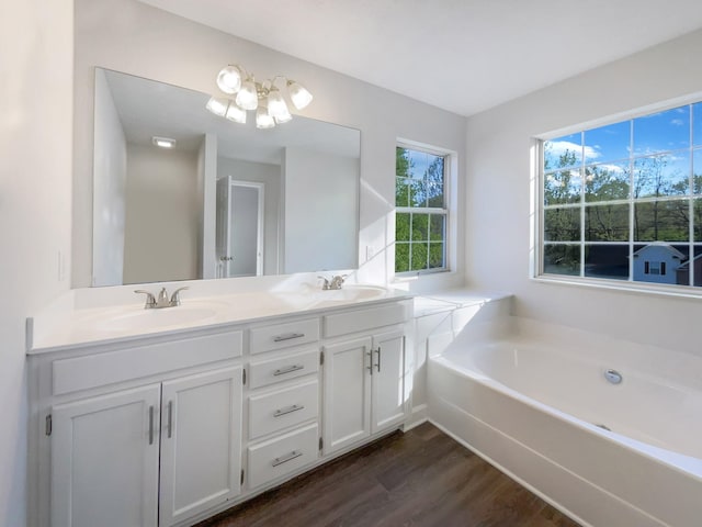 bathroom featuring double vanity, wood finished floors, a notable chandelier, and a sink