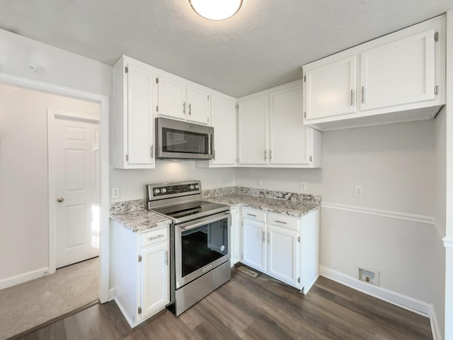 kitchen with white cabinets, baseboards, stainless steel appliances, and dark wood-type flooring