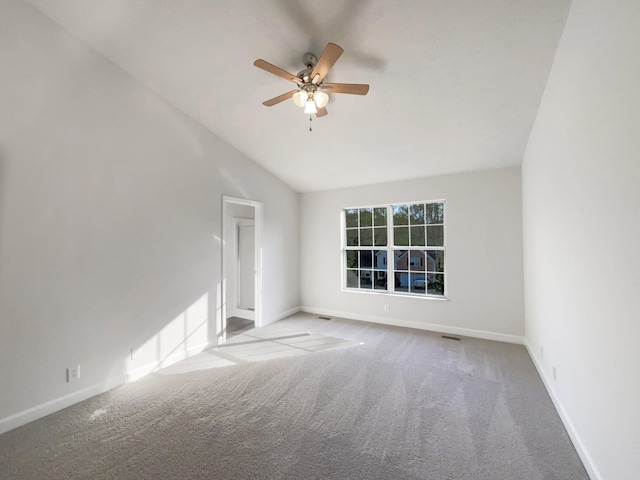 carpeted spare room with baseboards, a ceiling fan, vaulted ceiling, and visible vents