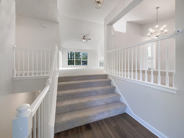 stairs featuring wood finished floors and ceiling fan with notable chandelier