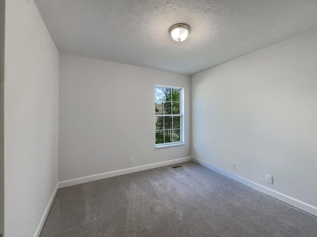carpeted spare room with visible vents, baseboards, and a textured ceiling