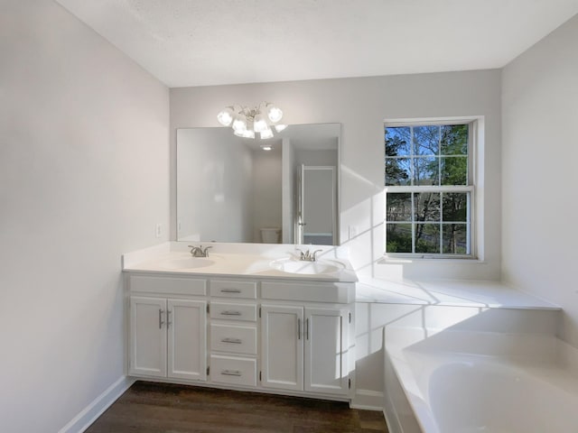 bathroom with a chandelier, double vanity, wood finished floors, and a sink