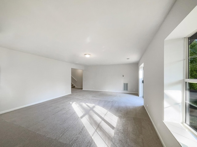 unfurnished living room featuring stairway, baseboards, visible vents, and carpet flooring