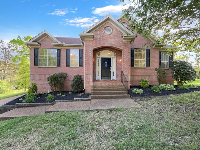 view of front facade with brick siding, entry steps, and a front lawn