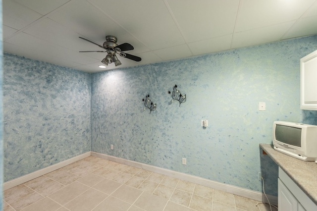 unfurnished room with a ceiling fan, a paneled ceiling, and light tile patterned floors