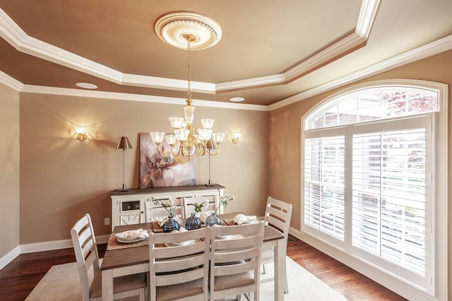 dining room with a raised ceiling, wood finished floors, crown molding, and an inviting chandelier