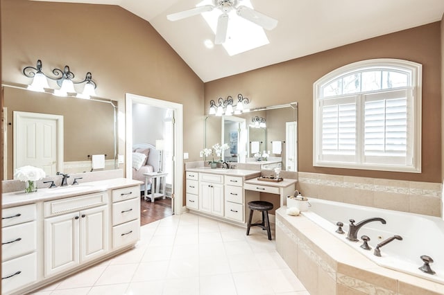 bathroom featuring a bath, ceiling fan, two vanities, and a sink
