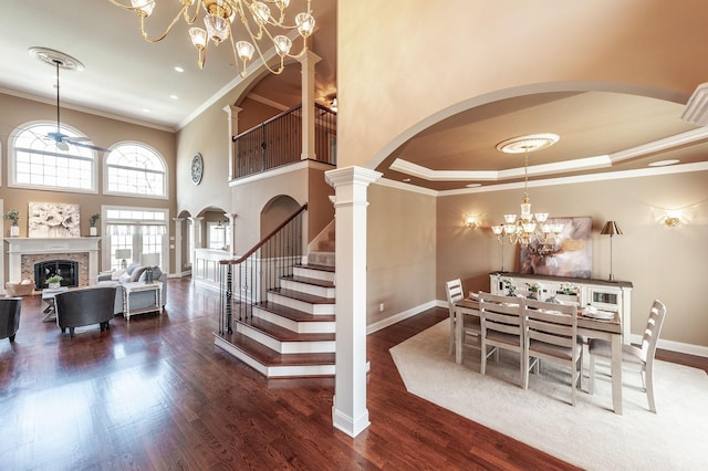 dining area with a chandelier, a glass covered fireplace, arched walkways, and ornamental molding