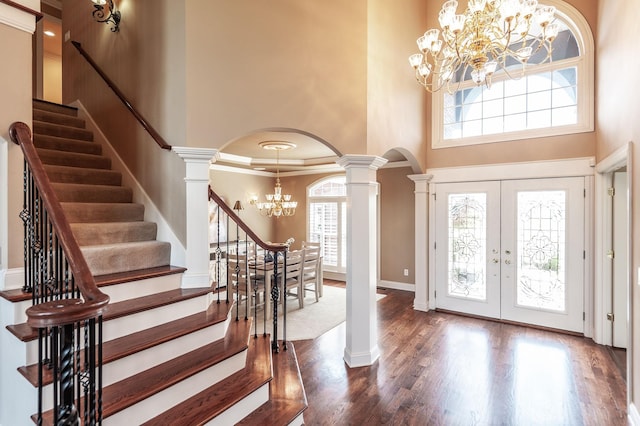 foyer entrance with arched walkways, french doors, a high ceiling, and an inviting chandelier