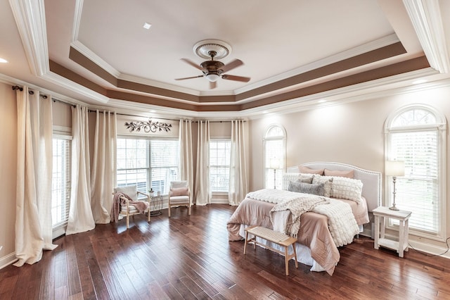 bedroom with a tray ceiling, dark wood-style floors, ornamental molding, and multiple windows