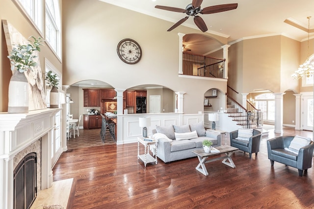 living area with wood finished floors, decorative columns, a towering ceiling, and ceiling fan