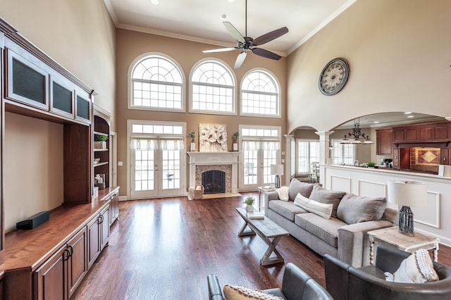 living room featuring a ceiling fan, a wealth of natural light, ornate columns, and crown molding