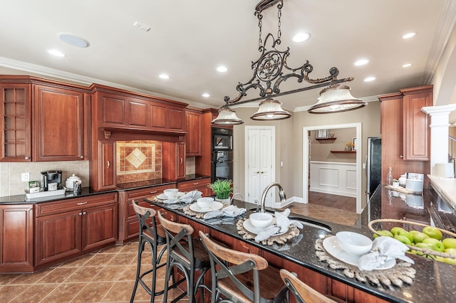 kitchen with decorative backsplash, a kitchen breakfast bar, black appliances, and ornamental molding