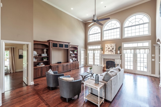 living area featuring a high ceiling, a ceiling fan, a glass covered fireplace, and a wealth of natural light