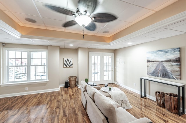 living area featuring baseboards, wood finished floors, and a tray ceiling