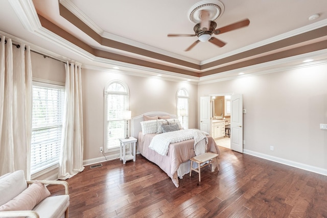 bedroom with a tray ceiling, dark wood-style flooring, baseboards, visible vents, and crown molding
