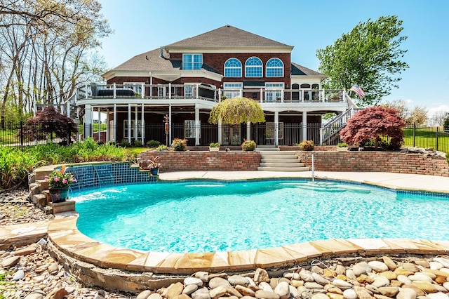 rear view of property with a fenced in pool, a balcony, stairway, and fence