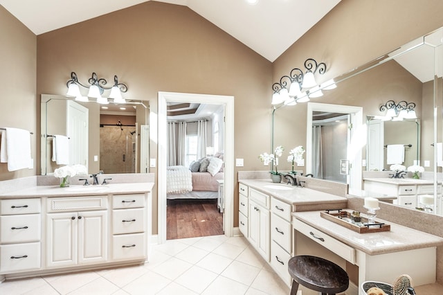 ensuite bathroom with vaulted ceiling, tile patterned floors, a sink, and a stall shower
