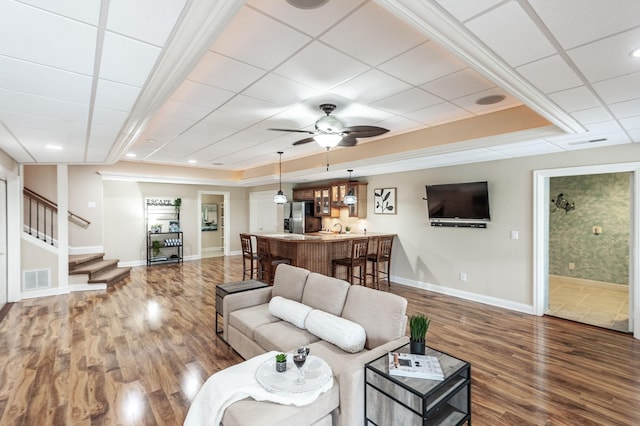 living room with baseboards, wood finished floors, visible vents, and stairs