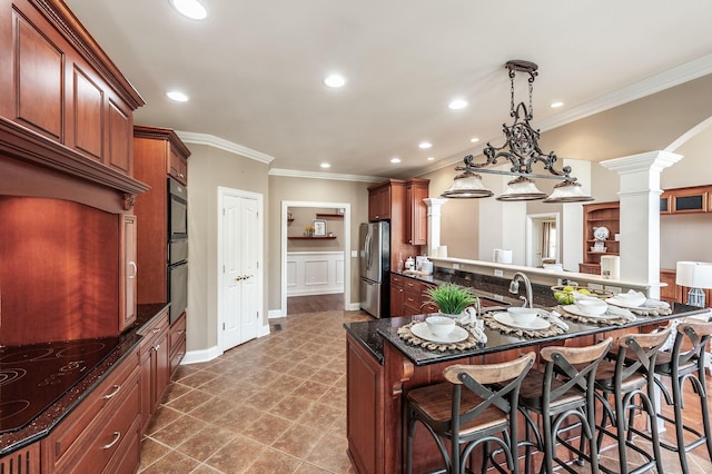 kitchen featuring ornate columns, a breakfast bar area, black electric stovetop, ornamental molding, and freestanding refrigerator
