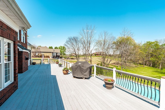 wooden terrace with a pool and a grill