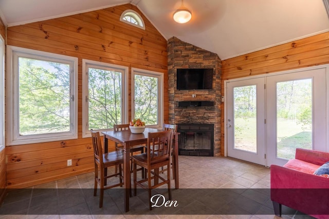 tiled dining area with lofted ceiling, wooden walls, and a fireplace