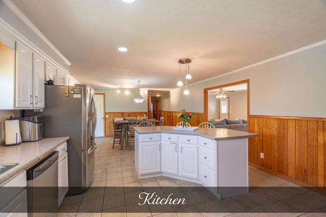 kitchen featuring white cabinets, stainless steel appliances, a wainscoted wall, and wooden walls