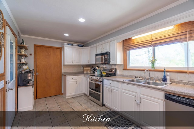 kitchen featuring a sink, light tile patterned flooring, stainless steel appliances, white cabinets, and ornamental molding