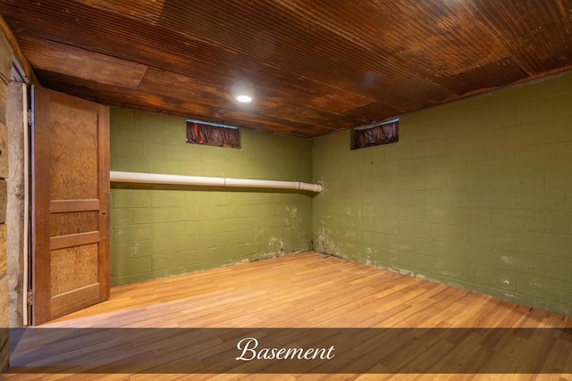 finished below grade area with wood ceiling, concrete block wall, and wood finished floors