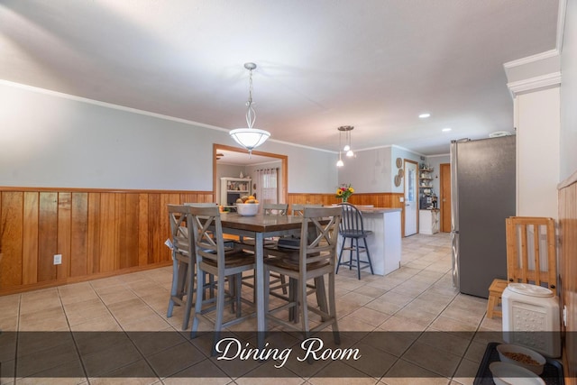 dining space featuring wooden walls, a wainscoted wall, ornamental molding, and light tile patterned floors