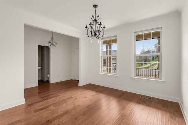 unfurnished dining area featuring a chandelier, wood finished floors, visible vents, and ornamental molding