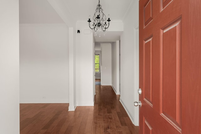 entrance foyer featuring crown molding, baseboards, dark wood-style flooring, and an inviting chandelier