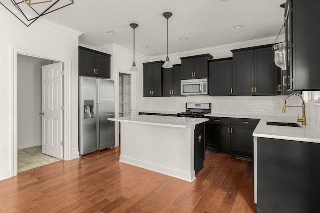 kitchen with decorative backsplash, appliances with stainless steel finishes, a sink, and a kitchen island