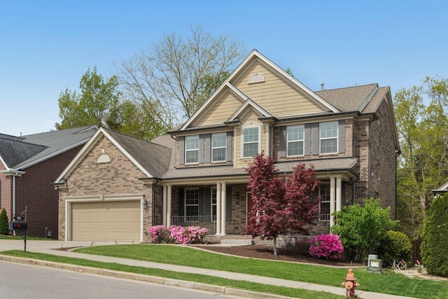 craftsman inspired home with a garage, brick siding, a porch, and driveway