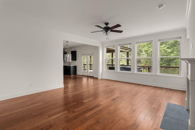 unfurnished living room featuring baseboards, visible vents, a ceiling fan, wood finished floors, and ornamental molding