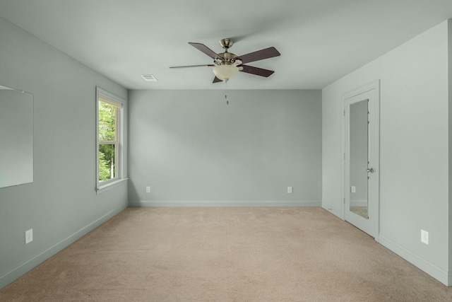unfurnished room with ceiling fan, light carpet, visible vents, and baseboards