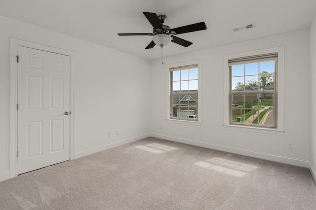 spare room featuring baseboards, a ceiling fan, visible vents, and carpet