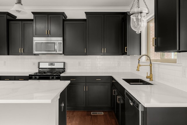 kitchen with stainless steel appliances, dark wood-style flooring, a sink, and hanging light fixtures